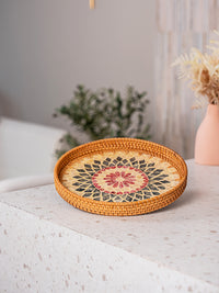 Handwoven round rattan serving tray with built-in handles for home decor.