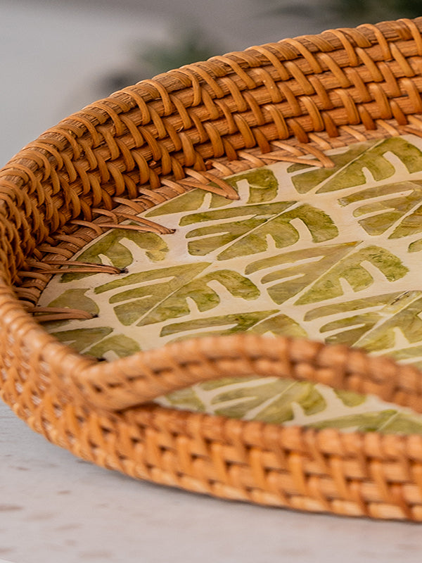 A closeup of handwoven natural rattan tray with two side handles and inlay design